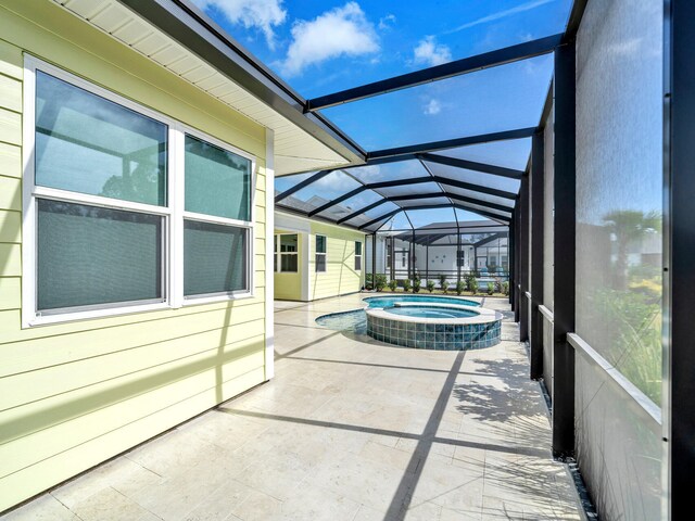 view of pool with a patio, glass enclosure, and an in ground hot tub