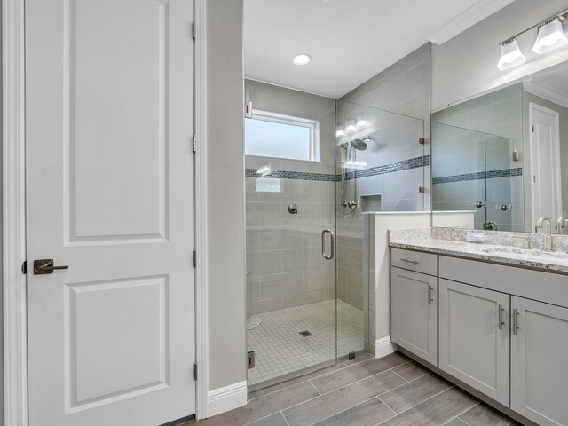 bathroom with an enclosed shower, vanity, and crown molding