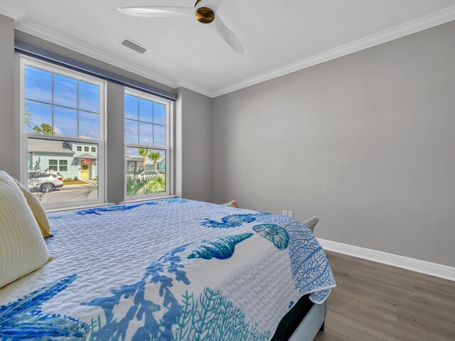 bedroom with ceiling fan, dark hardwood / wood-style floors, and ornamental molding