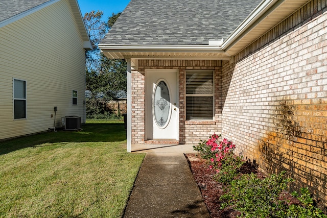 doorway to property with central AC unit and a yard