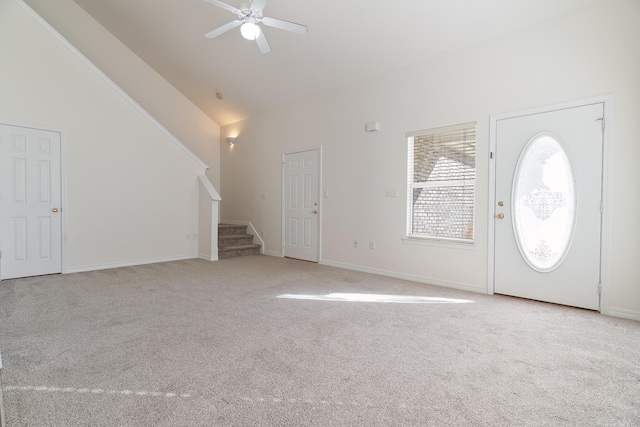 carpeted entryway with high vaulted ceiling and ceiling fan