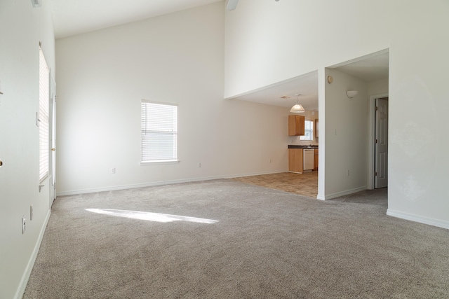 unfurnished living room with high vaulted ceiling and light carpet