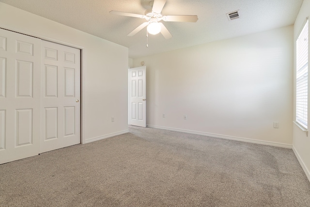 unfurnished bedroom featuring carpet floors, a textured ceiling, ceiling fan, and a closet