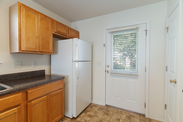 kitchen with a textured ceiling and white refrigerator