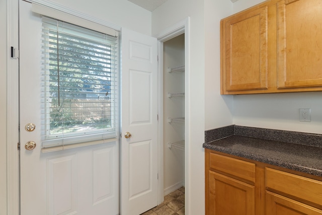 kitchen featuring plenty of natural light and dark stone countertops