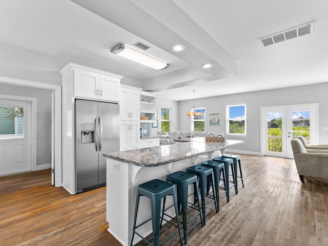 kitchen with white cabinetry, stone countertops, stainless steel refrigerator with ice dispenser, a breakfast bar, and dark wood-type flooring