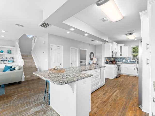 kitchen featuring a breakfast bar, appliances with stainless steel finishes, dark hardwood / wood-style floors, a kitchen island, and white cabinets