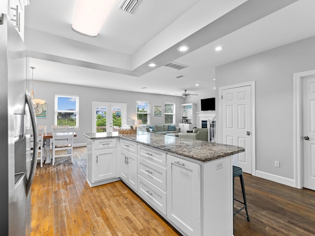 kitchen with a kitchen breakfast bar, stainless steel fridge with ice dispenser, white cabinetry, and light wood-type flooring