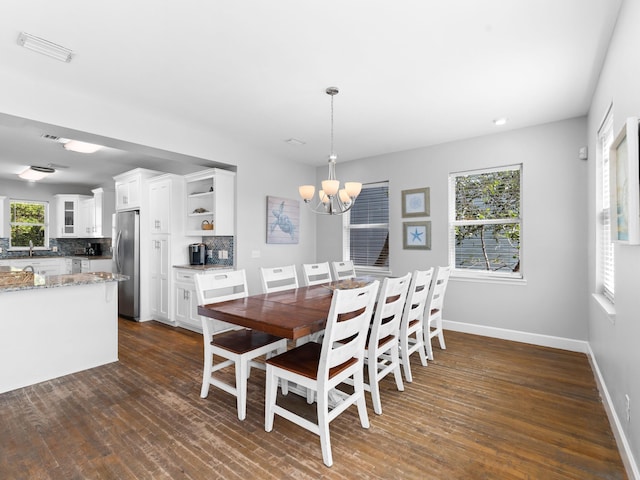 dining space with dark wood-type flooring and an inviting chandelier