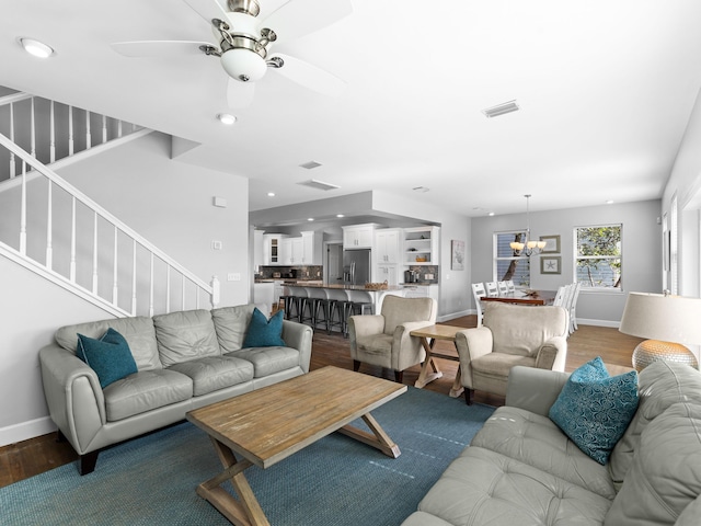 living room with ceiling fan with notable chandelier and dark hardwood / wood-style floors