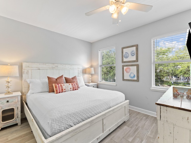 bedroom with ceiling fan, multiple windows, and light hardwood / wood-style floors