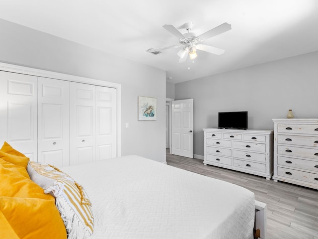 bedroom with light wood-type flooring, ceiling fan, and a closet