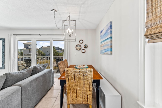 dining area featuring a notable chandelier, a textured ceiling, and light tile patterned floors