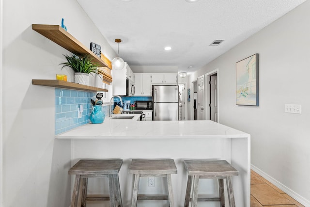 kitchen with stainless steel appliances, kitchen peninsula, a breakfast bar area, white cabinetry, and decorative light fixtures