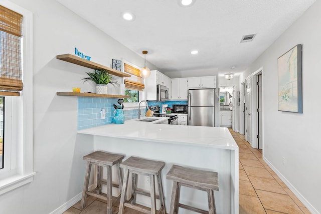 11 Beachside Dr Unit 1121, Santa Rosa Beach, FL 32459 - kitchen featuring stainless steel appliances, a peninsula, light countertops, light tile patterned floors, and backsplash