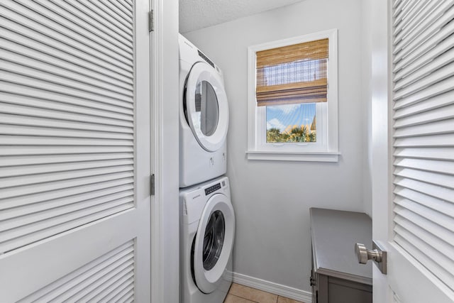 washroom featuring stacked washer and clothes dryer, a textured ceiling, and light tile patterned floors