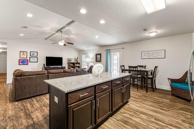 kitchen with a kitchen island, dark brown cabinets, dark hardwood / wood-style floors, lofted ceiling, and ceiling fan