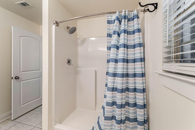 bathroom featuring walk in shower, a textured ceiling, and tile patterned floors