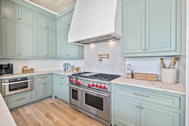 kitchen featuring appliances with stainless steel finishes, light wood-type flooring, wood ceiling, custom exhaust hood, and green cabinetry