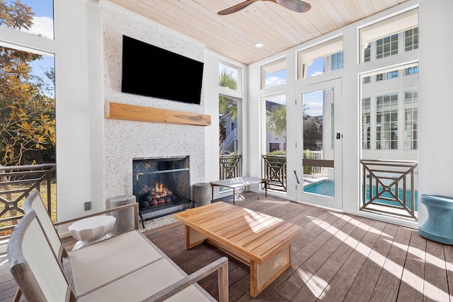 sunroom featuring ceiling fan, wooden ceiling, and a wealth of natural light