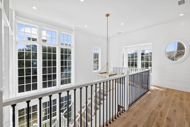 corridor with hardwood / wood-style flooring, a wealth of natural light, and crown molding