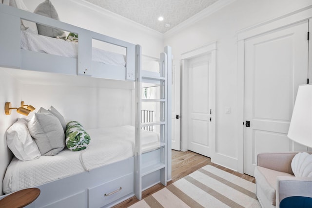 bedroom with crown molding, light hardwood / wood-style floors, and a textured ceiling