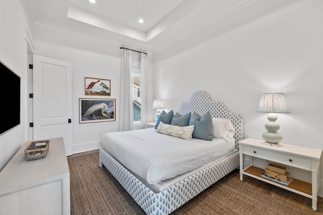 bedroom with dark hardwood / wood-style floors and a raised ceiling