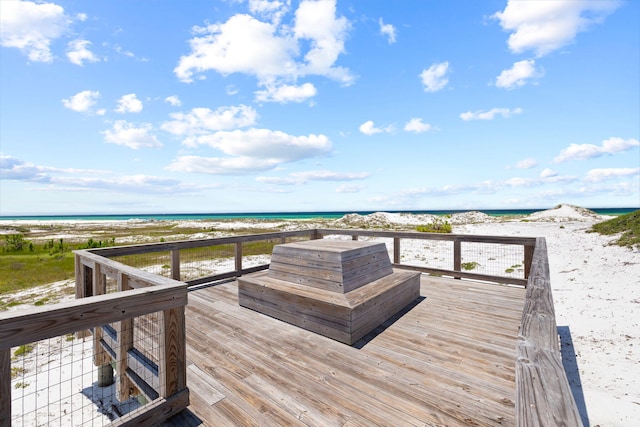 wooden deck featuring a water view and a beach view