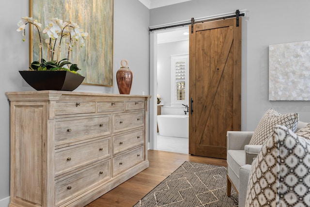 living area with light hardwood / wood-style flooring, a barn door, and crown molding