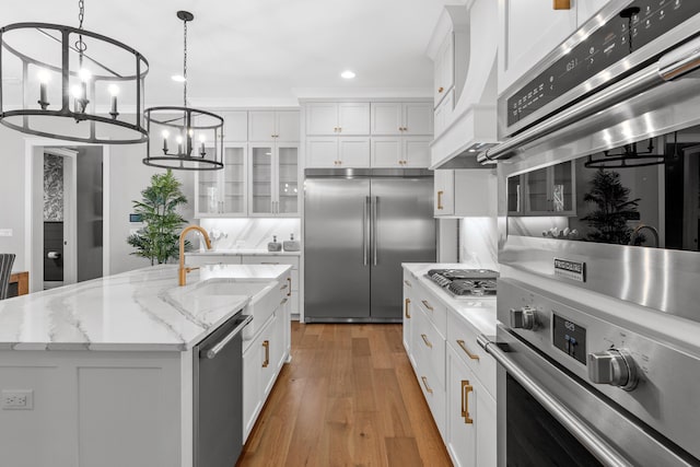 kitchen featuring white cabinets, stainless steel appliances, and an island with sink