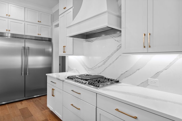 kitchen featuring custom exhaust hood, white cabinets, light hardwood / wood-style floors, and stainless steel appliances