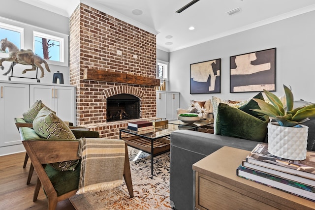 living room featuring ornamental molding, a brick fireplace, and light hardwood / wood-style floors