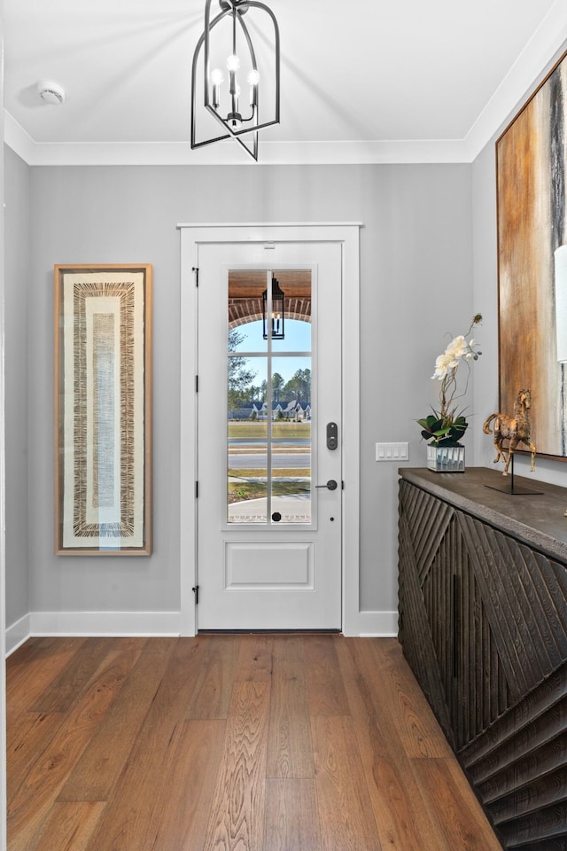 foyer entrance featuring hardwood / wood-style floors, a notable chandelier, and crown molding