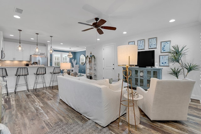 living room with dark hardwood / wood-style flooring, ceiling fan, and crown molding