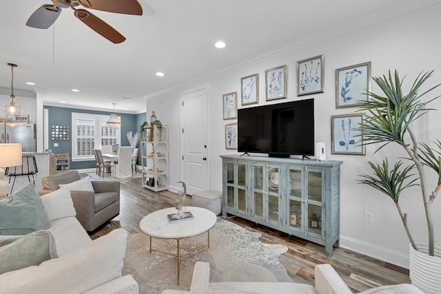 living room featuring ornamental molding, wood-type flooring, and ceiling fan