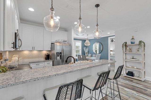 kitchen with stainless steel appliances, dark hardwood / wood-style flooring, light stone countertops, white cabinets, and a breakfast bar area