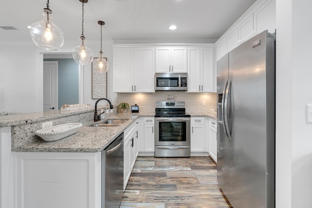 kitchen with stainless steel appliances, kitchen peninsula, sink, white cabinetry, and decorative light fixtures