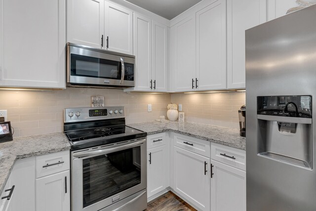 kitchen featuring stainless steel appliances, white cabinets, light stone counters, and tasteful backsplash