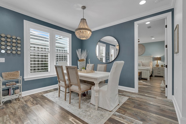 dining room with dark wood-type flooring, an inviting chandelier, and ornamental molding