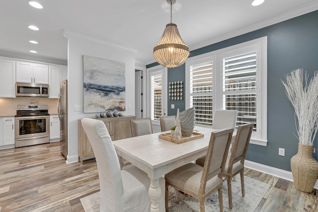 dining space featuring light wood-type flooring, crown molding, and an inviting chandelier