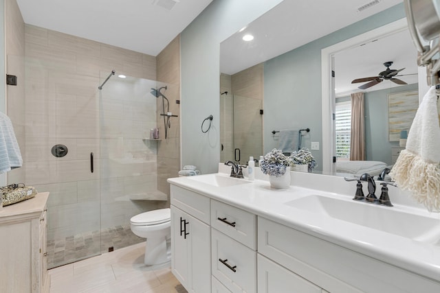 bathroom with tile patterned flooring, ceiling fan, vanity, an enclosed shower, and toilet