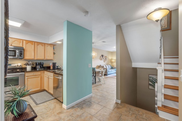 kitchen featuring appliances with stainless steel finishes, light brown cabinets, a sink, and dark countertops