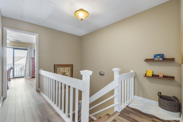 staircase featuring attic access, wood finished floors, and baseboards