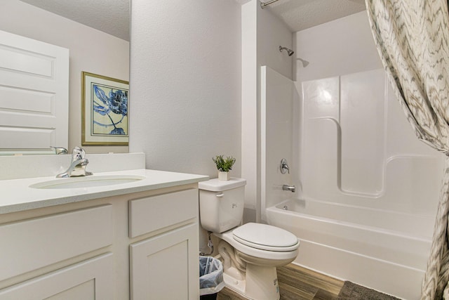 full bathroom featuring hardwood / wood-style flooring, a textured ceiling, vanity, bathtub / shower combination, and toilet