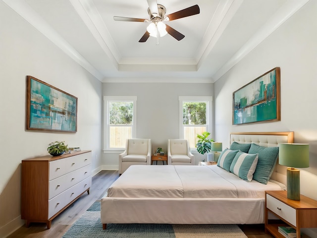 bedroom with light hardwood / wood-style floors, ceiling fan, and a raised ceiling