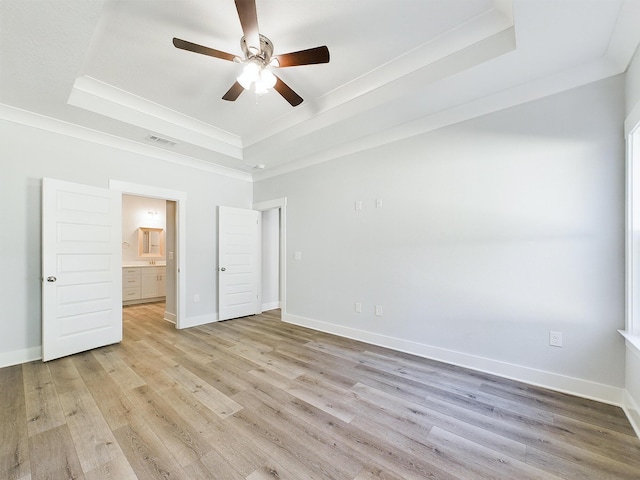 unfurnished bedroom featuring ceiling fan, connected bathroom, a tray ceiling, and crown molding