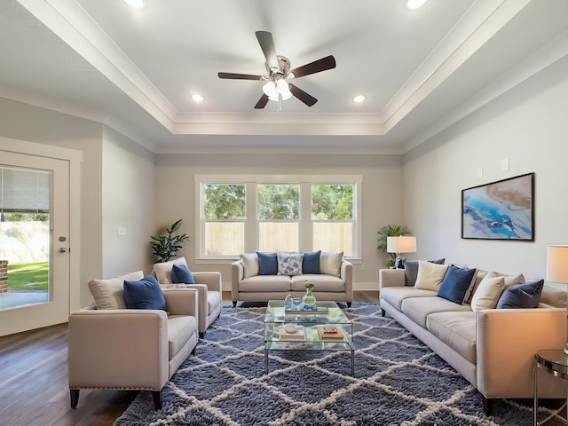 living room with ceiling fan, a raised ceiling, crown molding, and dark hardwood / wood-style flooring