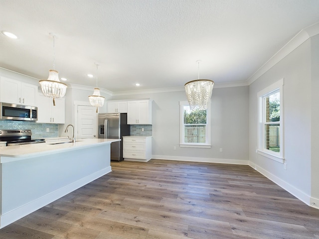 kitchen with pendant lighting, white cabinets, appliances with stainless steel finishes, tasteful backsplash, and an inviting chandelier