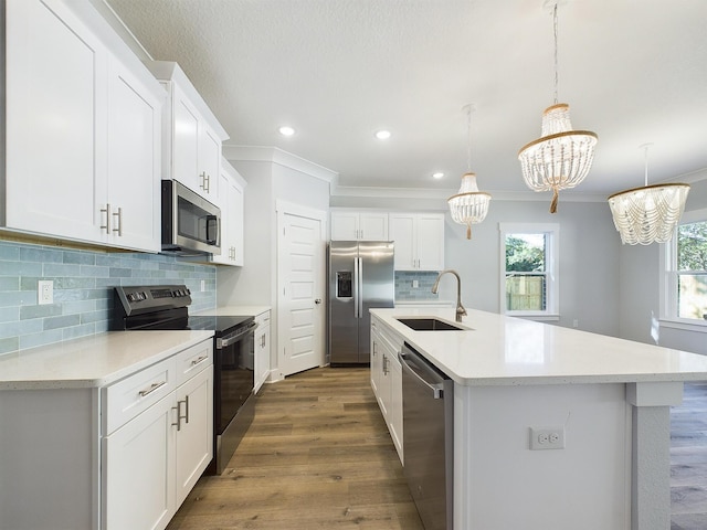 kitchen featuring sink, decorative light fixtures, white cabinets, a kitchen island with sink, and stainless steel appliances