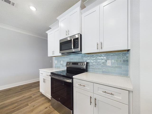 kitchen with crown molding, tasteful backsplash, white cabinets, light wood-type flooring, and stainless steel appliances